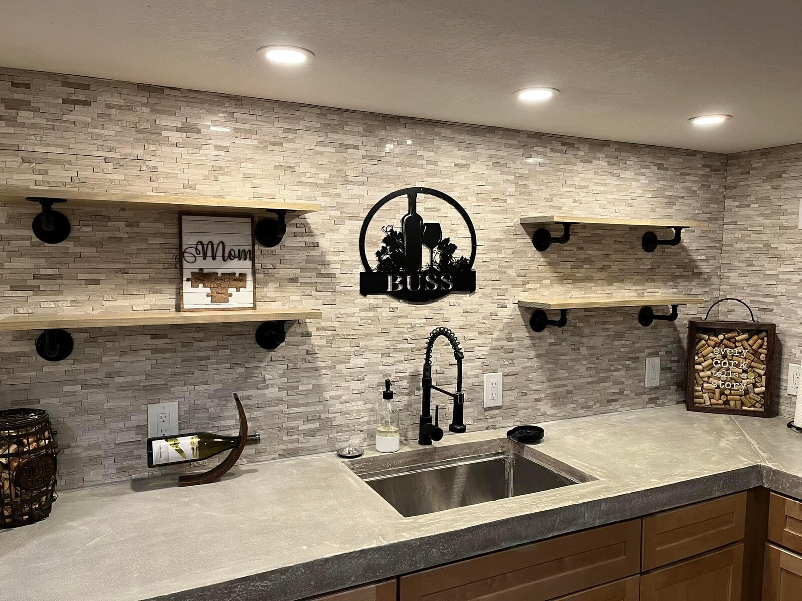 Custom wet bar with stone backsplash, wood shelves, and black fixtures